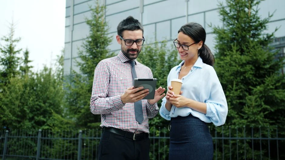 Personne analysant des graphiques d’entreprise avec un smartphone et un ordinateur portable sur le bureau.